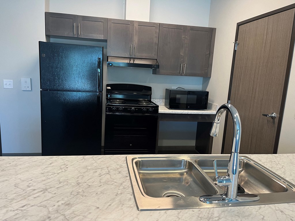 a kitchen with a sink and a black refrigerator