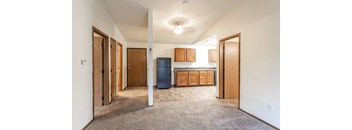 A room with a blue trash can and wooden cabinets.