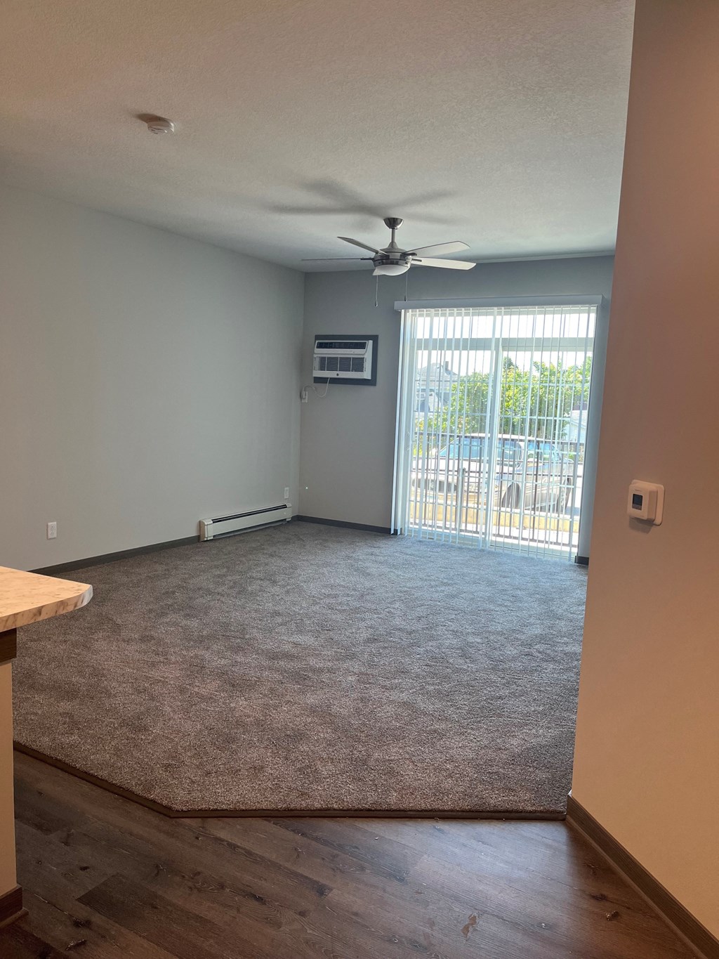 an empty living room with a ceiling fan and a window