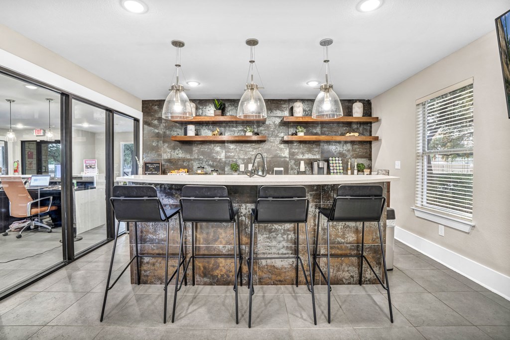 a kitchen with a bar and chairs in front of a window