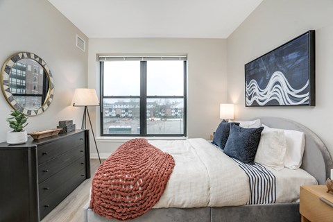 a bedroom with a large window and a bed with a blanket and pillows at Beekman on Broadway, Ann Arbor, MI