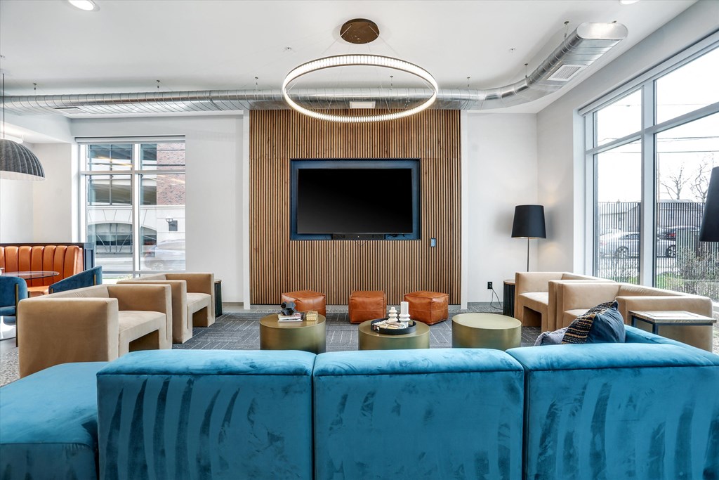 a living room with blue couches and chairs and a television at Beekman on Broadway, Ann Arbor