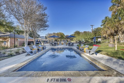a swimming pool with chairs around it and a patio with umbrellas  at Sunset Ridge, Texas