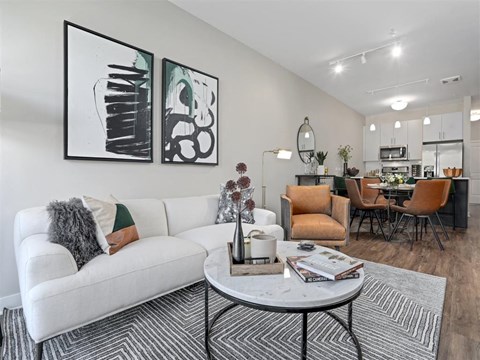 A living room with a white couch and two abstract paintings on the wall.