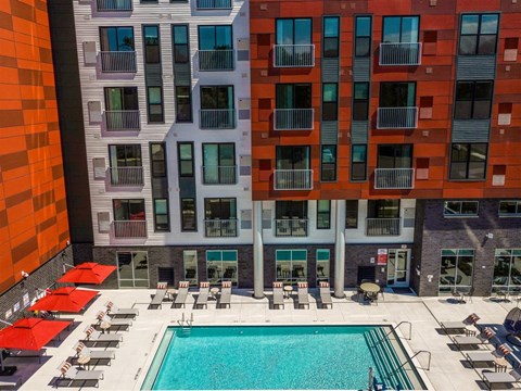 A large swimming pool surrounded by sun loungers in front of a building.