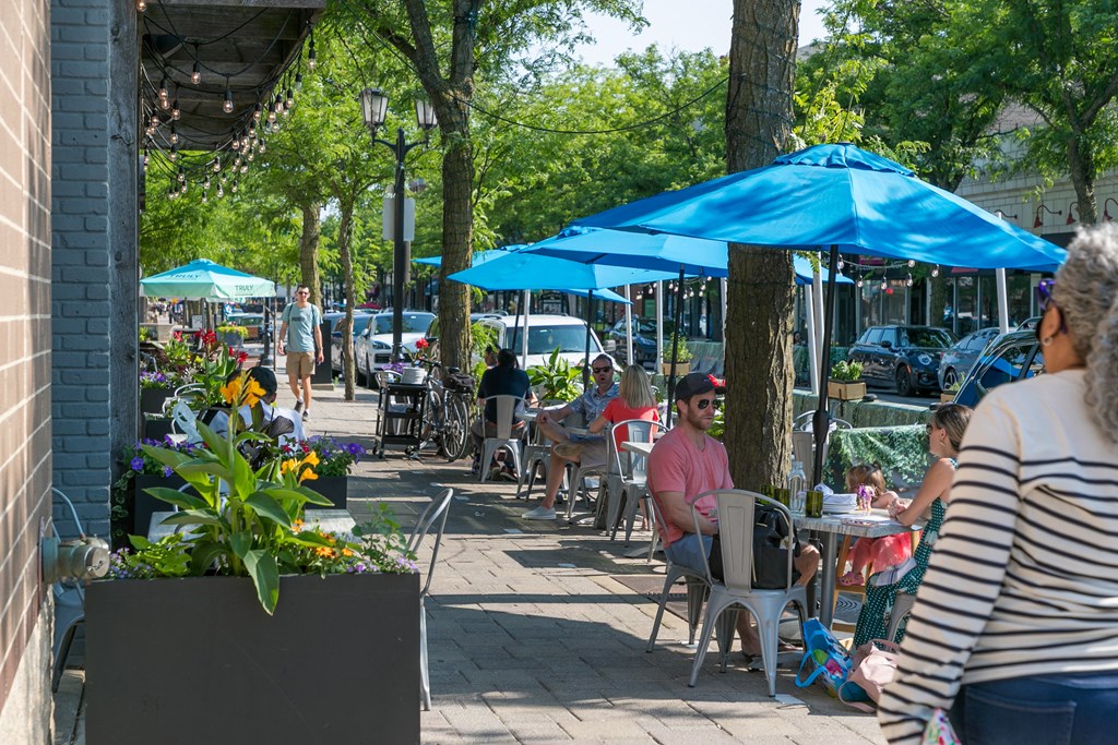 people sitting at tables under umbrellas on a sidewalk  at Elmhurst 255, Elmhurst, Illinois