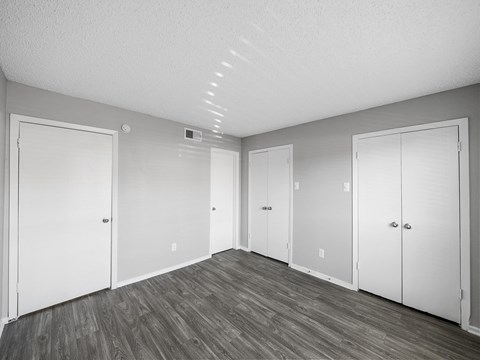 the living room of an apartment with white doors and wood flooring