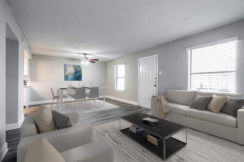 A living room with a grey couch, a coffee table, and a dining table set up.