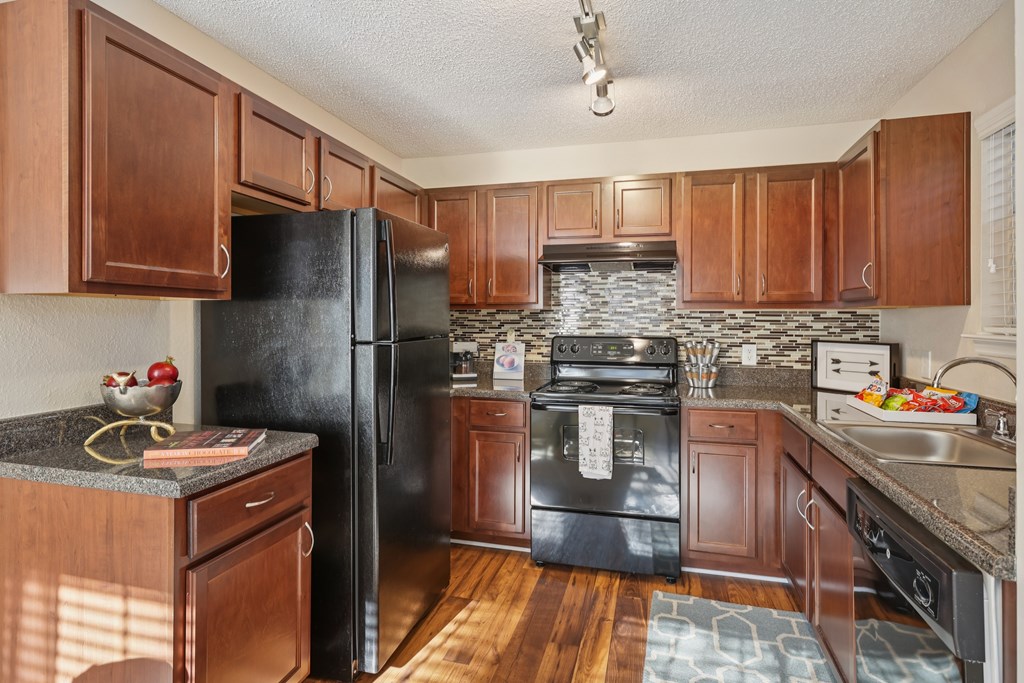 A kitchen with wooden cabinets and a black refrigerator.