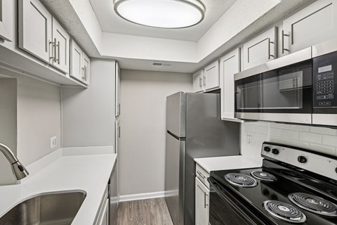 A kitchen with a black stove top oven and a black microwave above it.