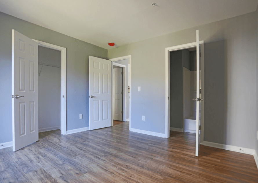 an empty living room with wood floors and white doors at Creekside Canopy, Charlotte  