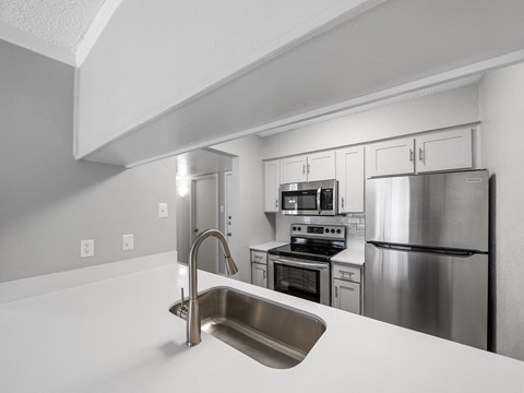 an empty kitchen with stainless steel appliances and a sink