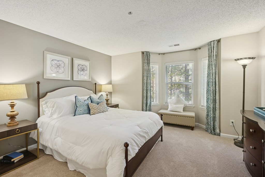 A bedroom with a large bed and a window with curtains.