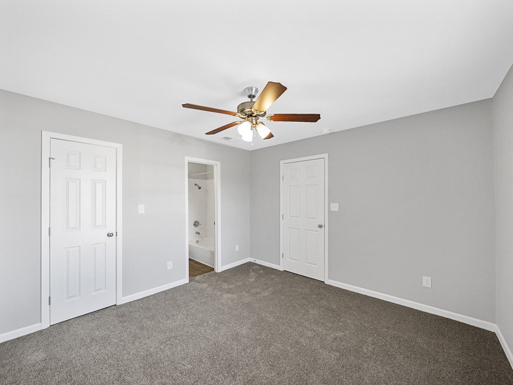 an empty room with a ceiling fan and a door to a closet