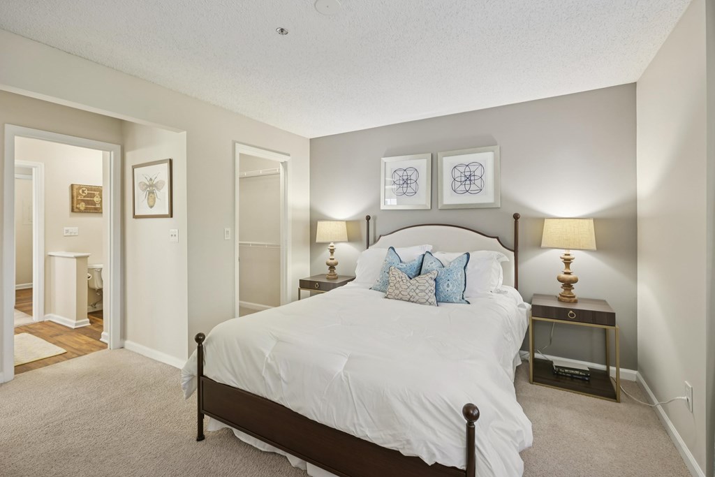 A bedroom with a large bed and two lamps.