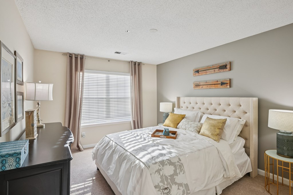 A bedroom with a large bed and a nightstand with a lamp.