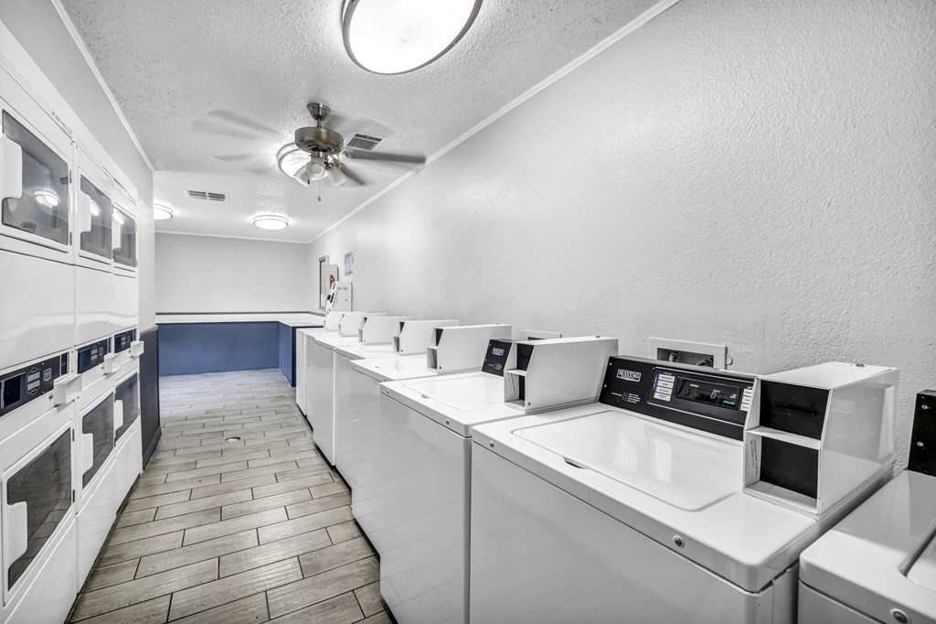 a laundry room with many washers and dryers and a ceiling fan