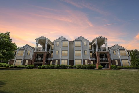 A large, modern apartment complex with multiple balconies and a well-manicured lawn in front.