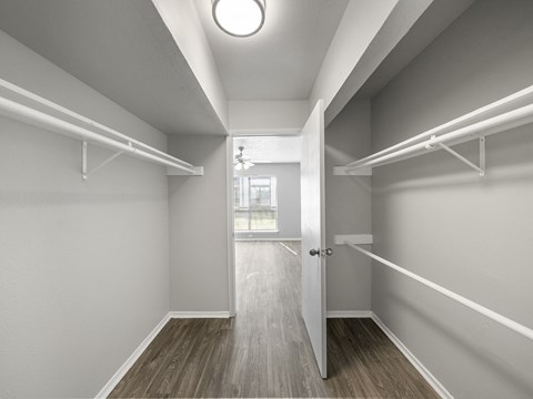 an empty room with white shelves and a door to a closet