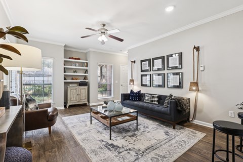 A living room with a black couch and a ceiling fan.