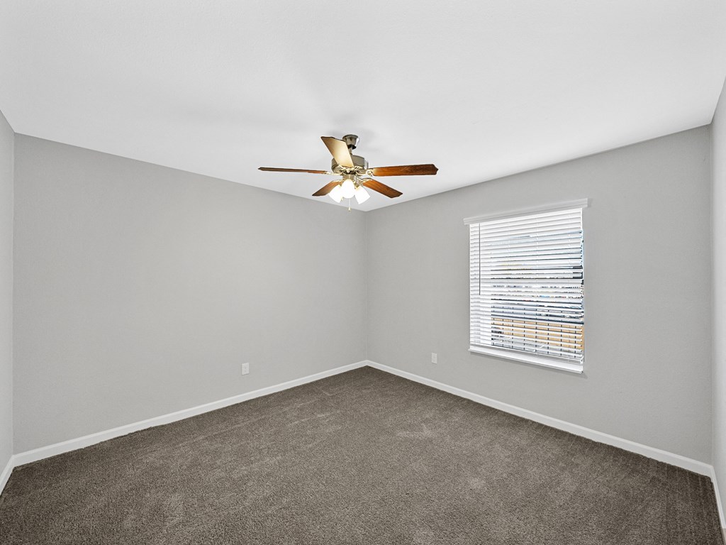 an empty room with a ceiling fan and a window