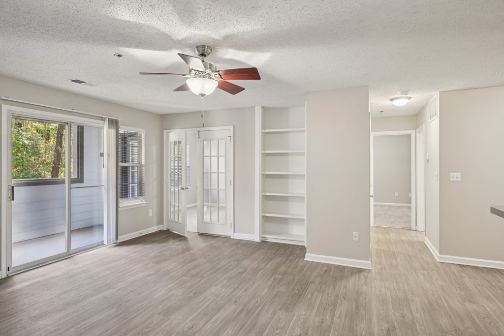 A room with a ceiling fan and sliding glass doors.