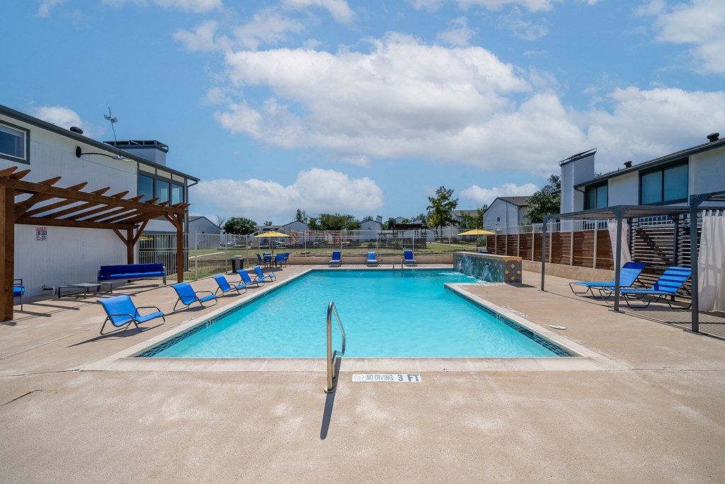 Pool with relaxing chairs around  at The Stella, Irving, TX