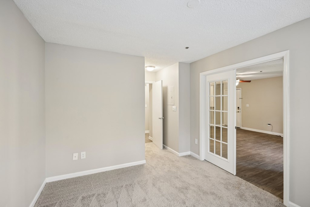 A room with a carpeted floor and a white door.