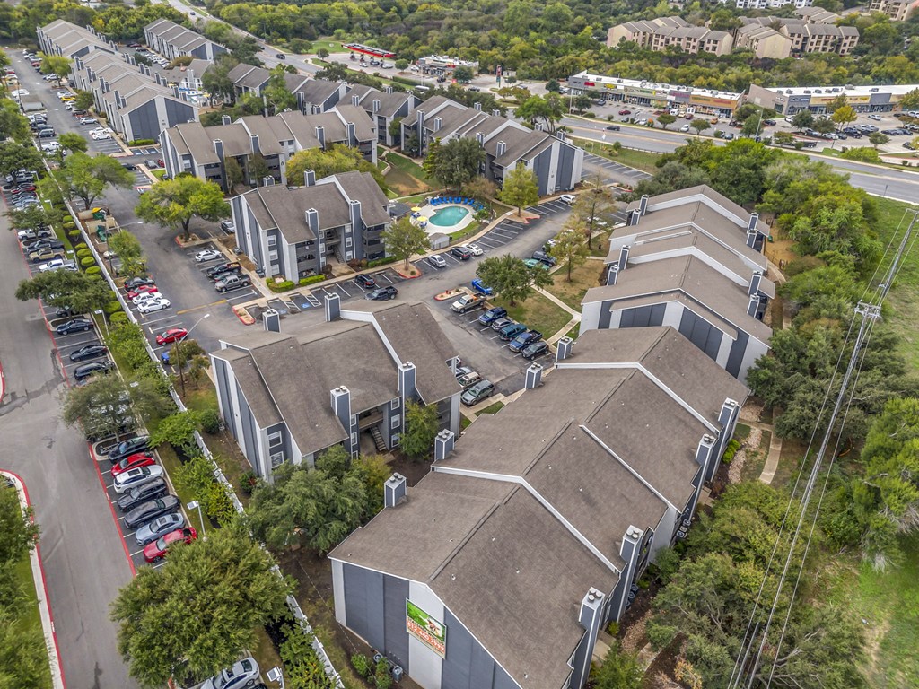 an aerial view of several buildings with cars parked in a parking lot