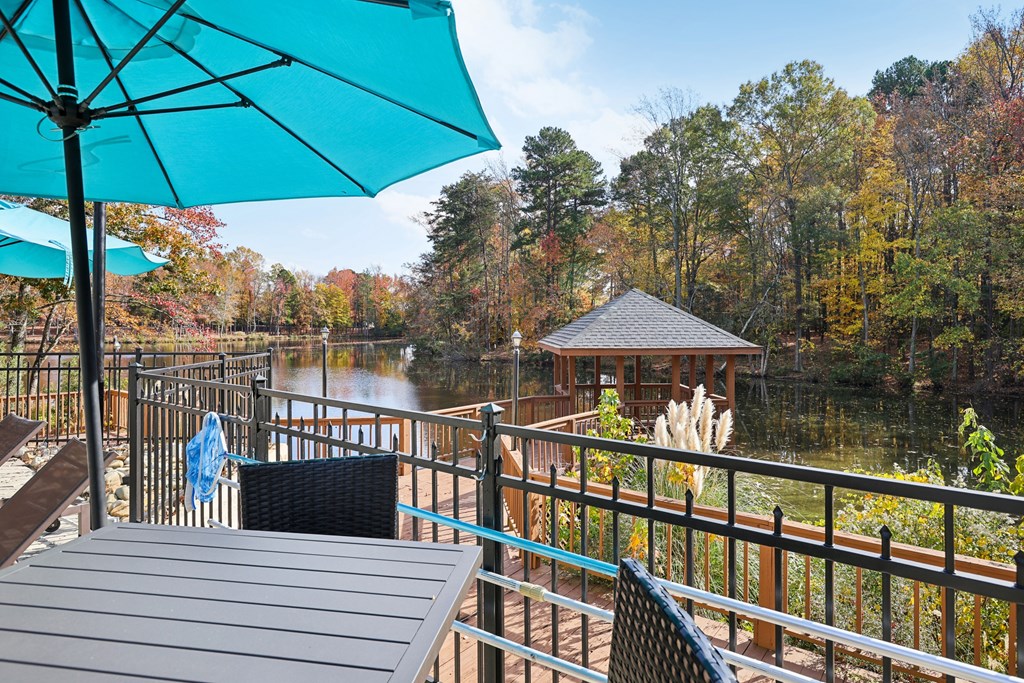A blue umbrella is on a table in front of a lake.