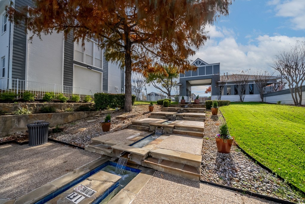 steps leading up to a house with a lawn and trees
