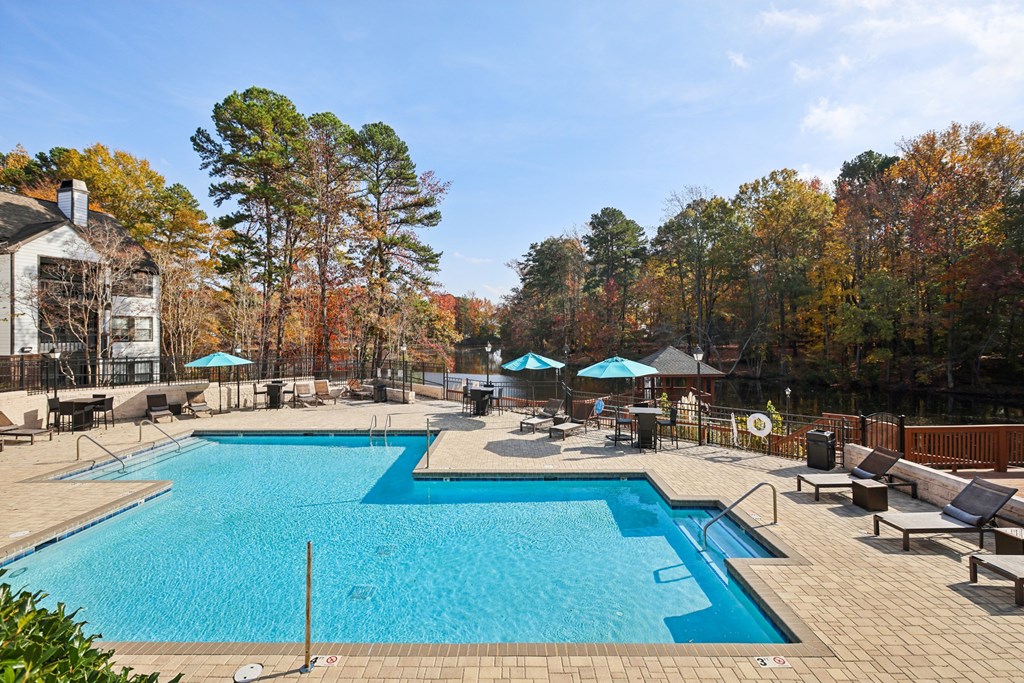 A large outdoor swimming pool surrounded by trees and a building.