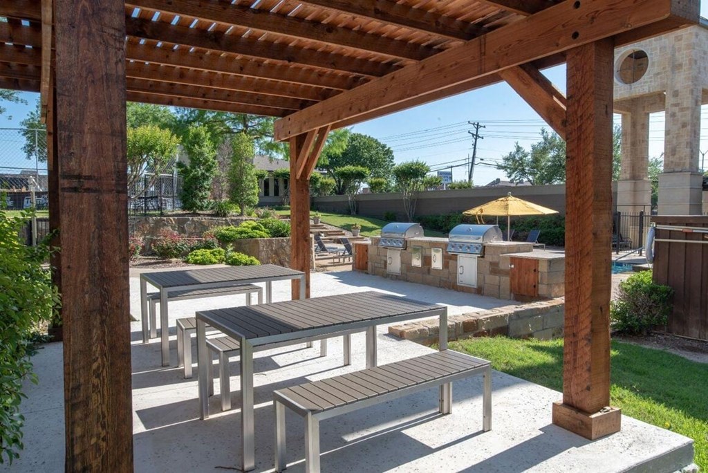 a patio with tables and benches and a pergola