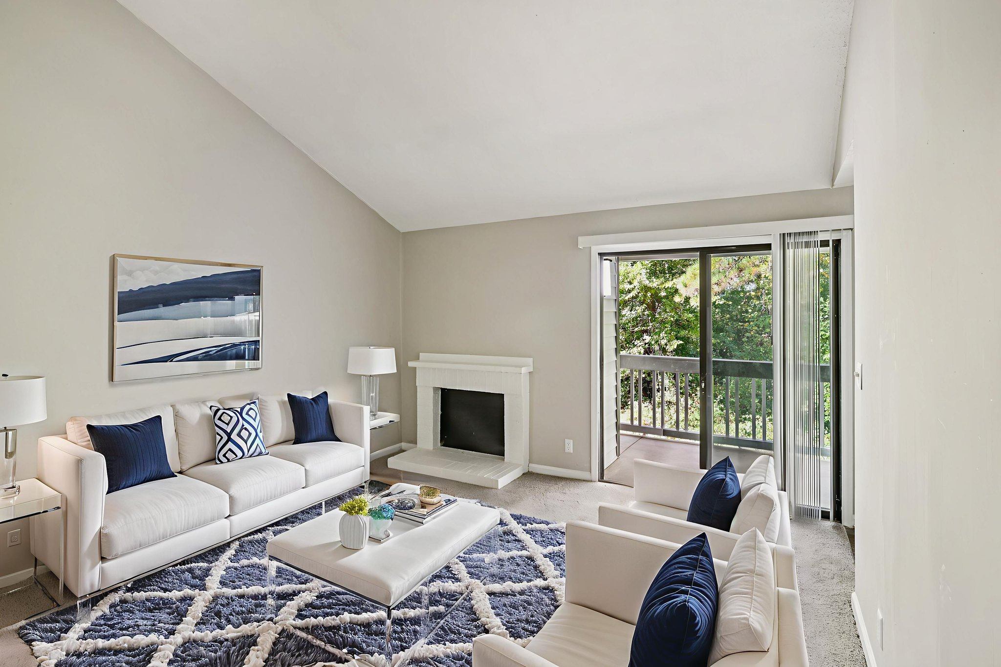 A living room with a white couch and a blue rug.