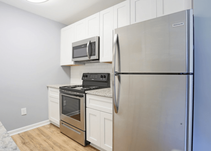 a kitchen with stainless steel appliances and white cabinets at Creekside Canopy, Charlotte North Carolina  