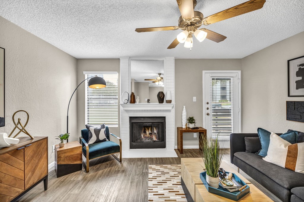 an open living room with a fireplace and a ceiling fan