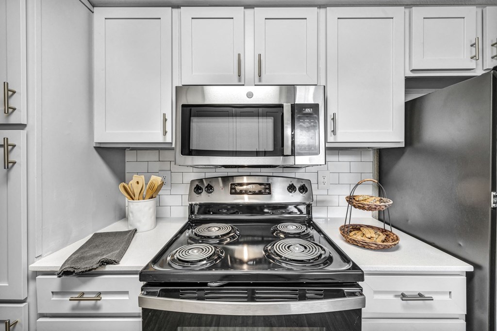a kitchen with white cabinets and a stove and a microwave