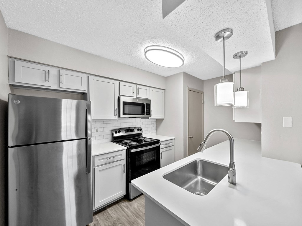 Kitchen with white cabinets and stainless steel appliances at Trinity Apartments, Irving, Texas