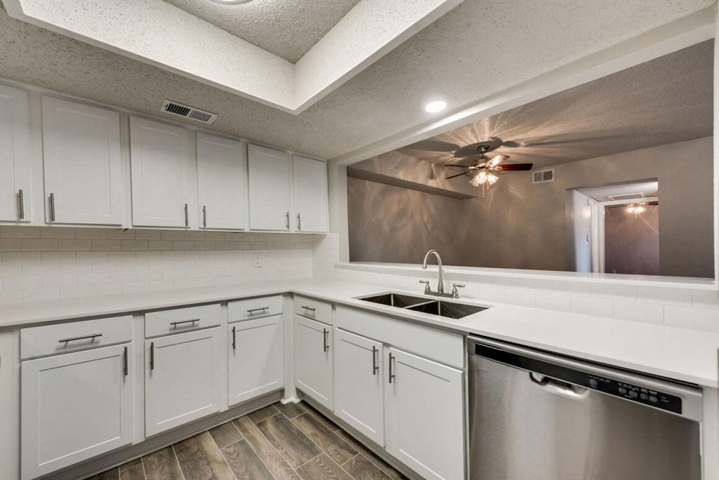 a kitchen with white cabinets and a sink and a ceiling fan