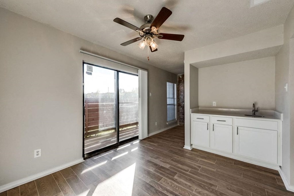 an empty living room with a ceiling fan and a window