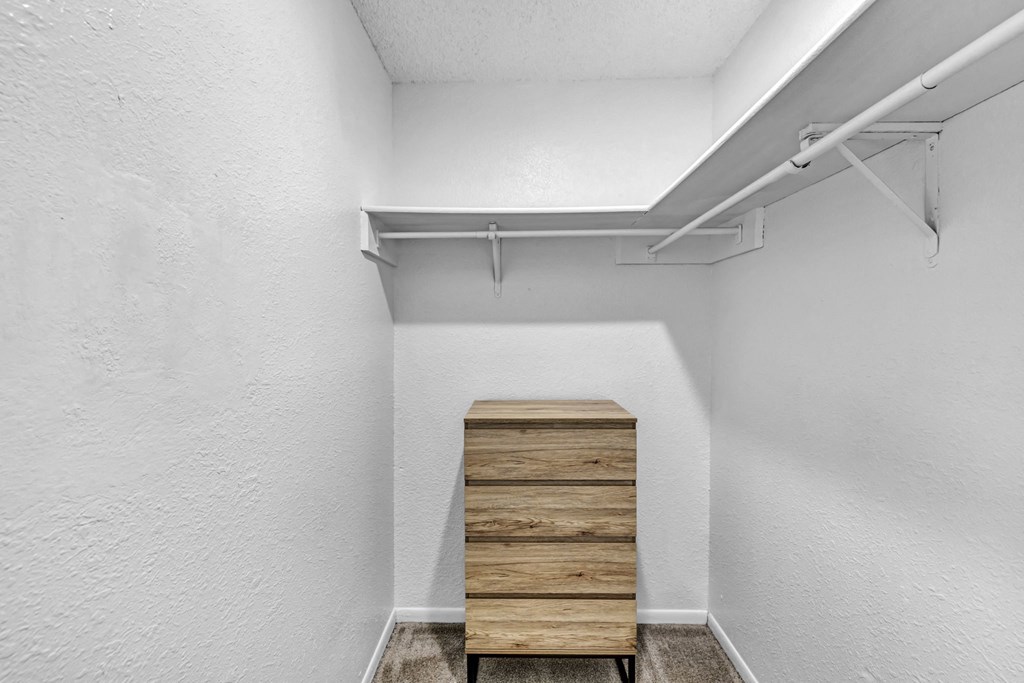 room with white walls and a wooden chest of drawers in the corner