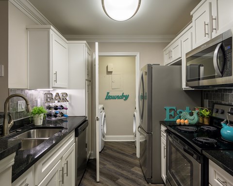 A kitchen with a black counter top and white cabinets.