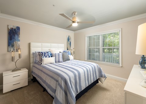 A bedroom with a bed, nightstands, and a ceiling fan.