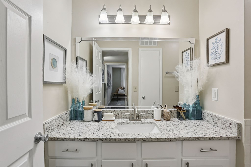 A bathroom with a marble countertop and a large mirror above it.