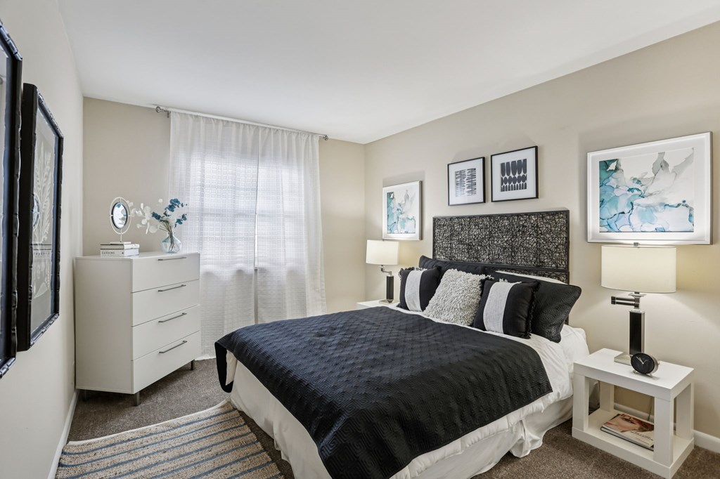 A bedroom with a black bedspread and white furniture.