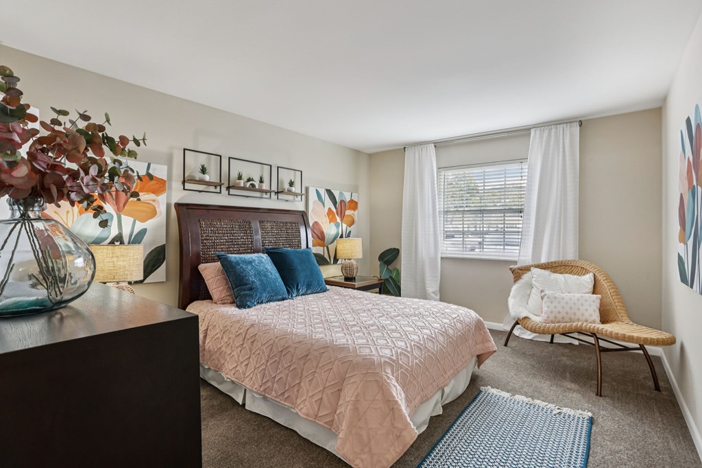 A bedroom with a bed, chair, and pictures on the wall.