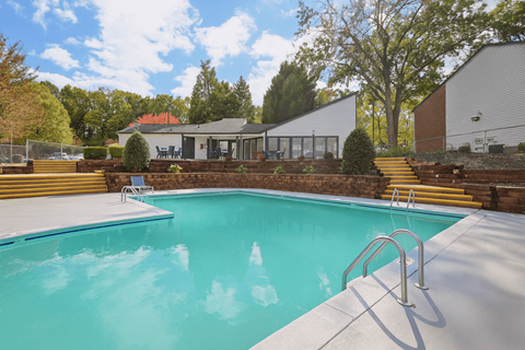 A swimming pool with a diving board and steps leading to a house.