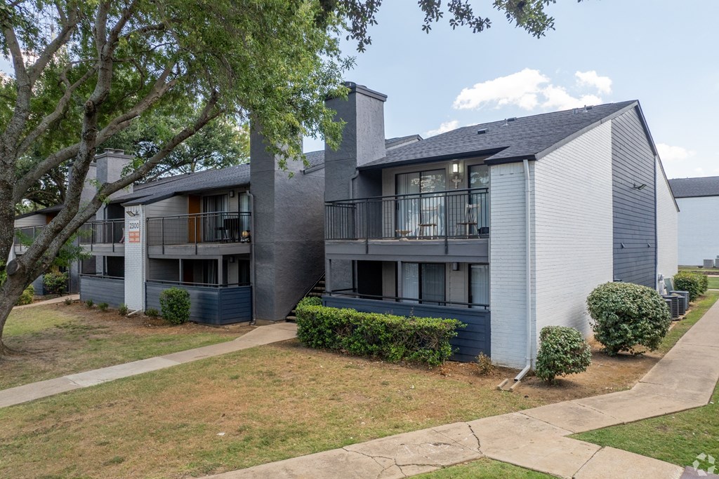a grey and blue apartment building with balconies and a sidewalk at District 2308, Arlington, 76011 