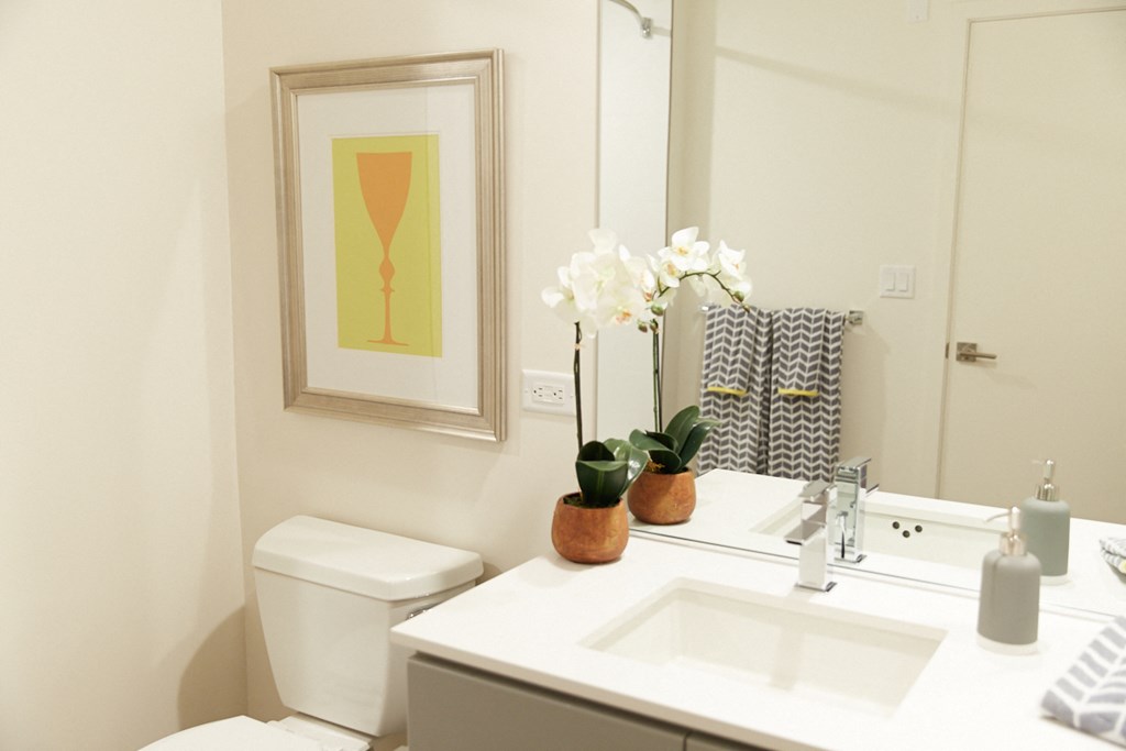 a white bathroom with a mirror and a sink and a toilet