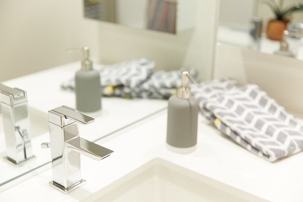a bathroom sink with a bottle of soap and a mirror